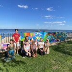 (PHOTO: Rye Arts Center teacher and muralist Ann Ladd with student painters and pRYEde organizers at the unveiling for the 2021 Pride mural.)