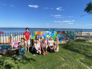 (PHOTO: Rye Arts Center teacher and muralist Ann Ladd with student painters and pRYEde organizers at the unveiling for the 2021 Pride mural.)