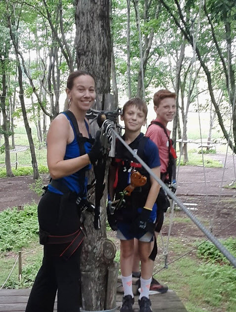 (PHOTO: Suzanne Short, Interim Principal of Rye High School, navigating a ropes course with her two teenage boys.)