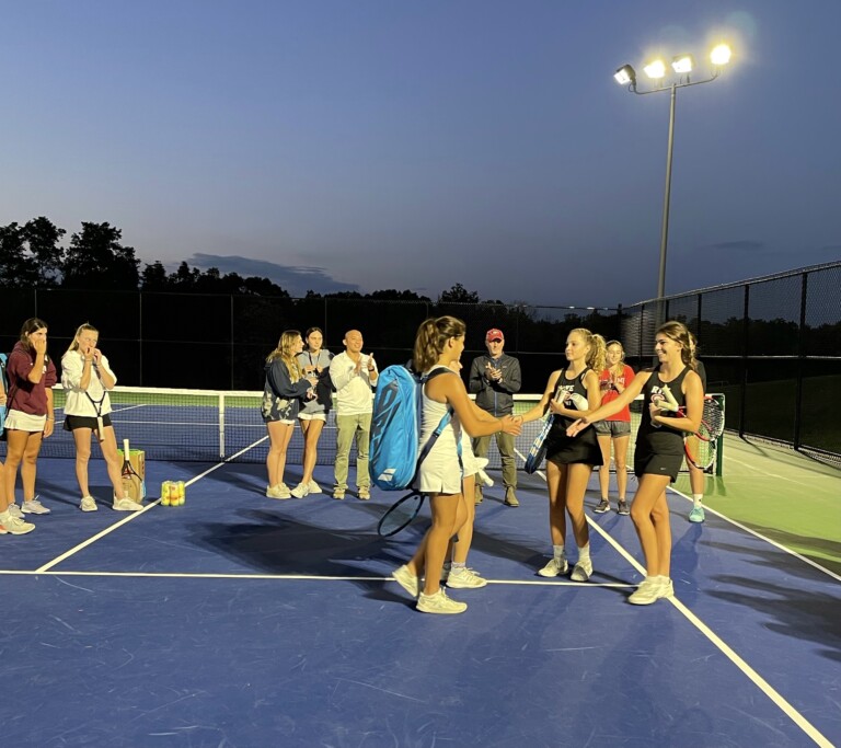 (PHOTO: Abby Davies and Cate Hartman are introduced under the lights at Harrison High School before going out to win their doubles match in straight sets 7-5, 7-6 (9-7).)