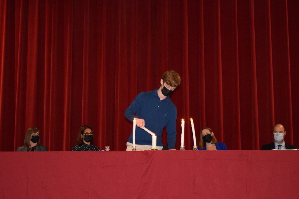 (PHOTO: Lighting the candles for the 2021 members of the National Honor Society. Daniel Roberts lights the candle representing character.)