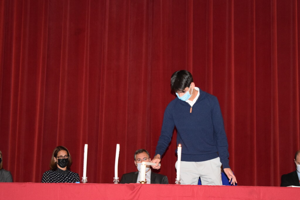 (PHOTO: Lighting the candles for the 2021 members of the National Honor Society. Rafay Syed lights the candle representing leadership.)