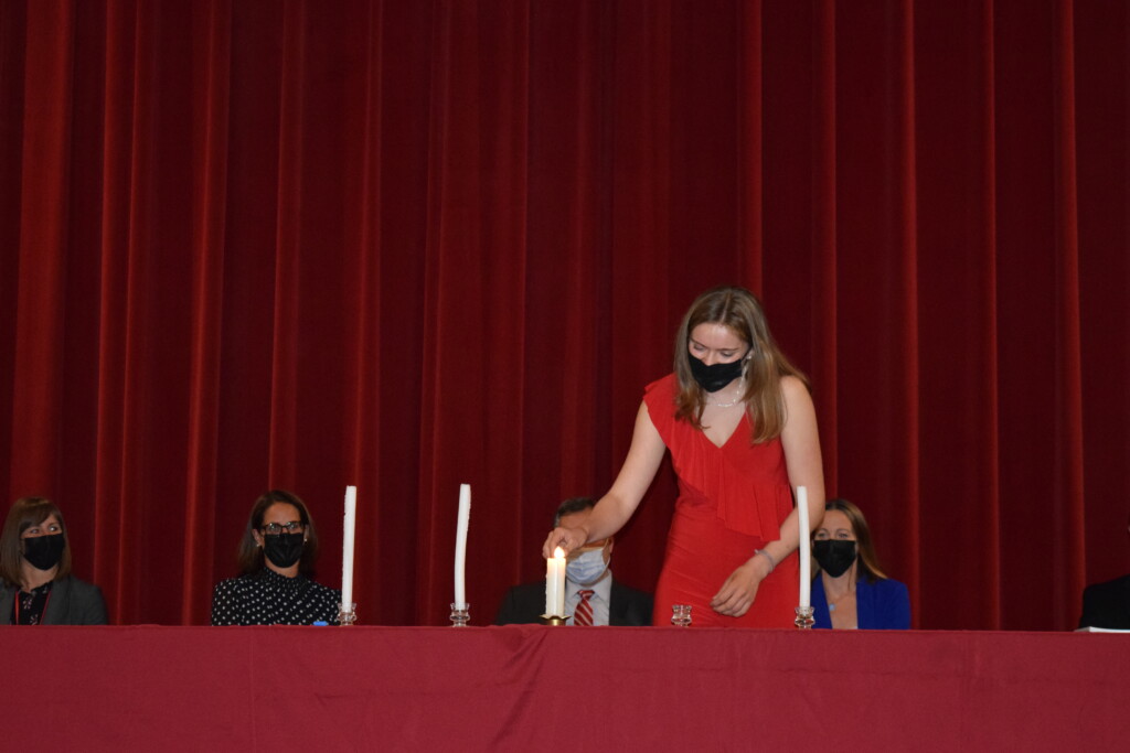 (PHOTO: Lighting the candles for the 2021 members of the National Honor Society. Vanessa Lahrkamp lights the candle representing scholarship.)