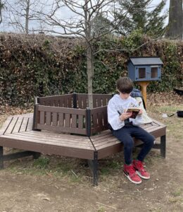 (PHOTO: A student reading on the bench at the Barbara Pierce Bush Memorial Mini Library, Milton School.)