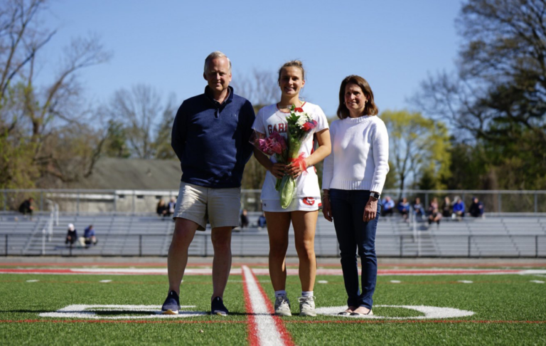 (PHOTO: Senior Ellie Hedges with her mom and dad during Saturday's senior day celebration.)