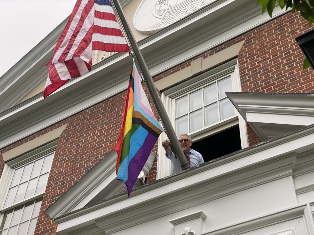 (PHOTO: Rye City Manager Greg Usry hoists the Pride flag onto the Rye City Hall flagpole   at the 2nd Annual Pride flag raising.)