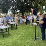 (PHOTO: Michele Thomas, president of Rye Rotary, addresses the assembled crowd at the unveiling of the Rye’sAbove butterflies on the Village Green.)