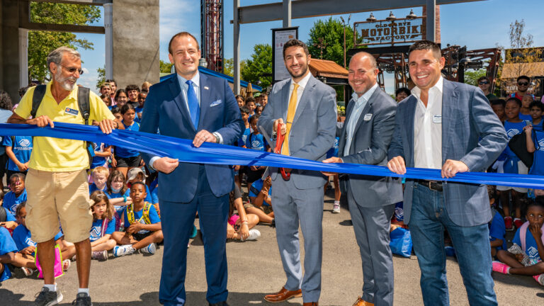 (PHOTO: Gashi, second from left, at the Playland ribbon cutting event. Left to right: Damon Maher, Westchester County Legislator, 10th District; Vedat Gashi - Westchester County Legislator, 4th District; David J. Tubiolo - Westchester County Legislator, 14th District; Ernest Blundell – General Manager, Standard Amusements and Nicholas Singer – Founder, Standard Amusements. The children are from the New Rochelle Boys and Girls Club (in blue) and Boy Scouts of Rye (in green and beige).)