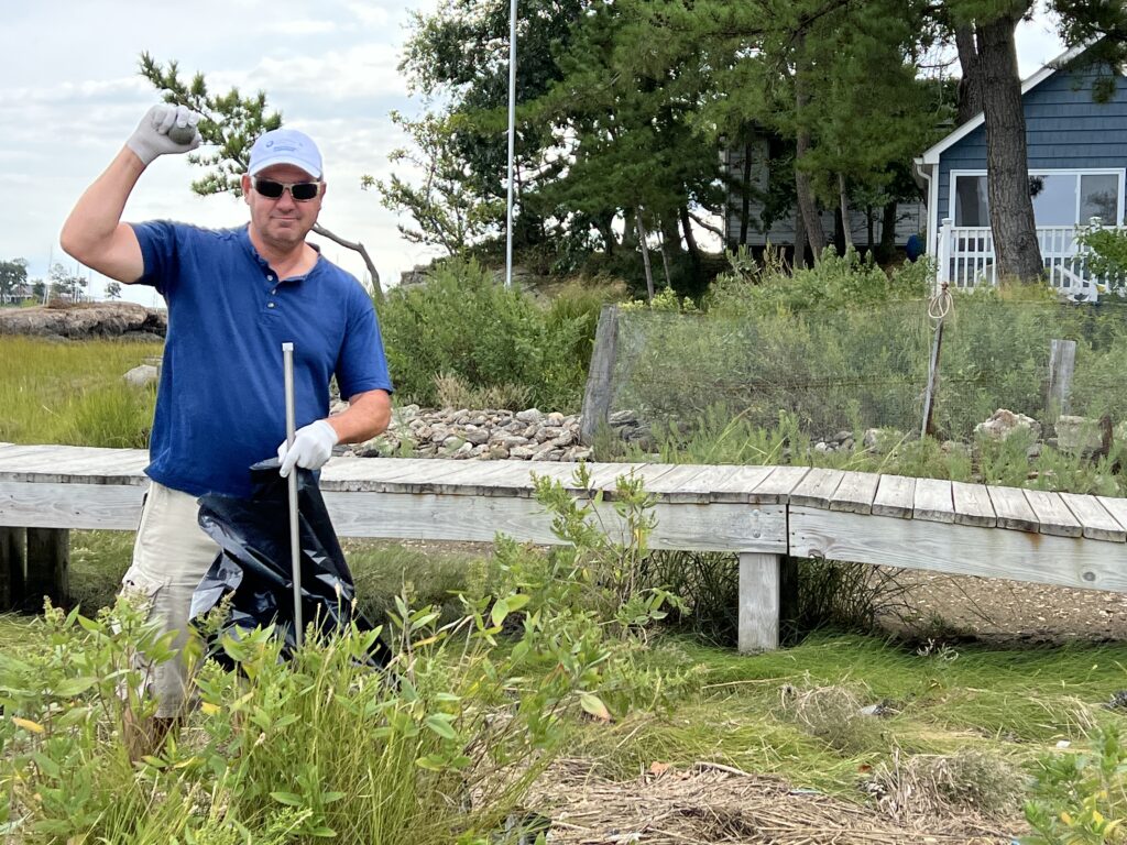 (PHOTO: Dan Goldsmith bagging the flotsam and jetsam during Hen Island beach cleanup day on Saturday, September 17, 2022.)