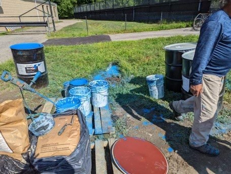 (PHOTO: The drums of paint used by National Installation – GC Corp that was spilled on the ground and into the local waterway.)
