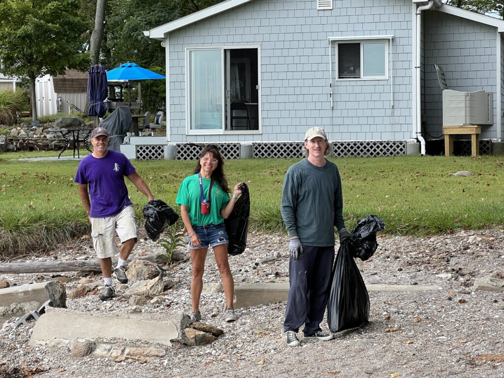 (PHOTO: Ed Volpe, Terri Volpe and Kevin Price bagging the flotsam and jetsam during Hen Island beach cleanup day on Saturday, September 17, 2022.)