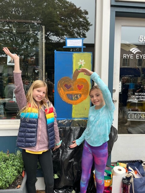 (PHOTO: Osborn School students, Nora Smyth and Coco Lax, showcase their window and positive message about peace for Ukraine at Rye Eye Care.)