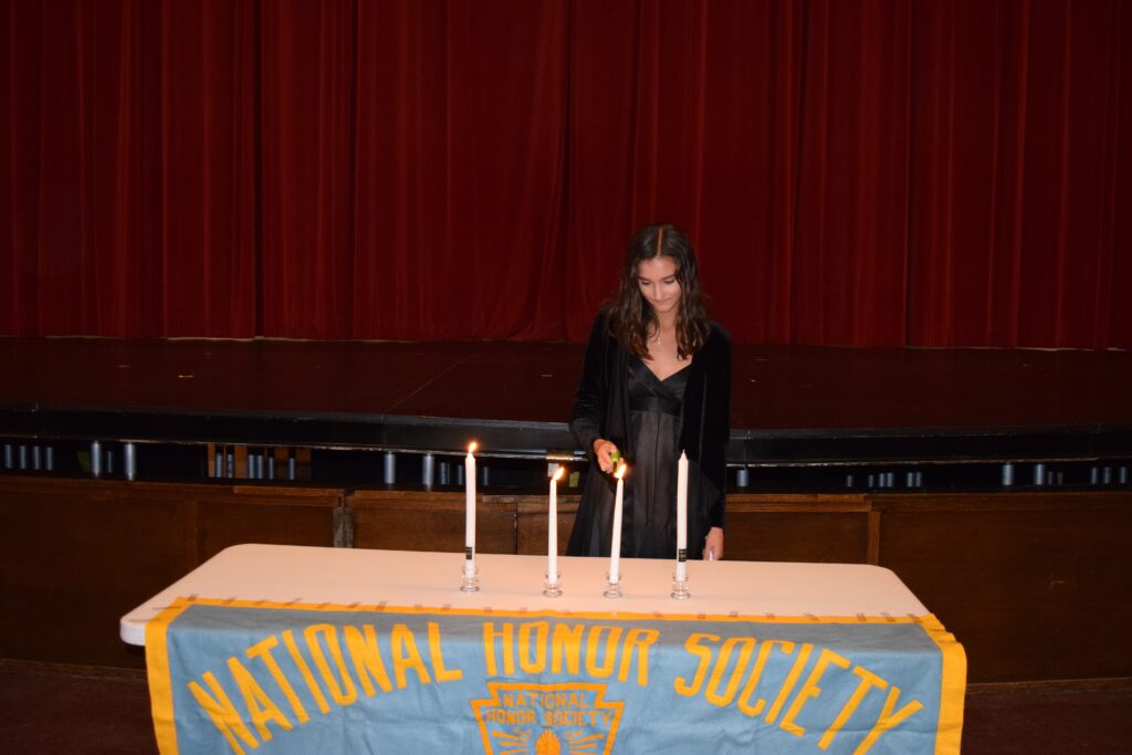 (PHOTO: Julia Cabrera lit the Candle of Service at the National Honor Society Induction on Monday, October 3, 2022 at Rye High School.)