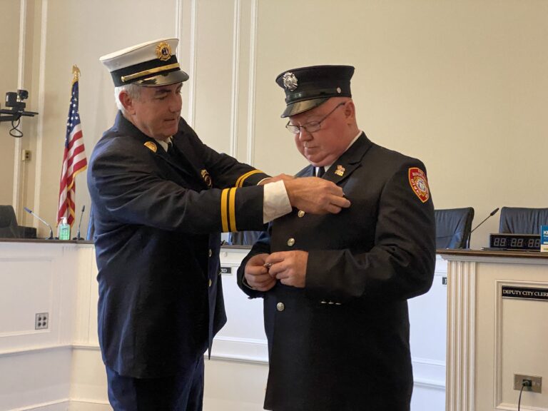 (PHOTO: Rye FD Captain John McDwyer puts the new pin on Lieutenant John Thompson at his Rye City Hall swearing in on Tuesday, October 18, 2022.)