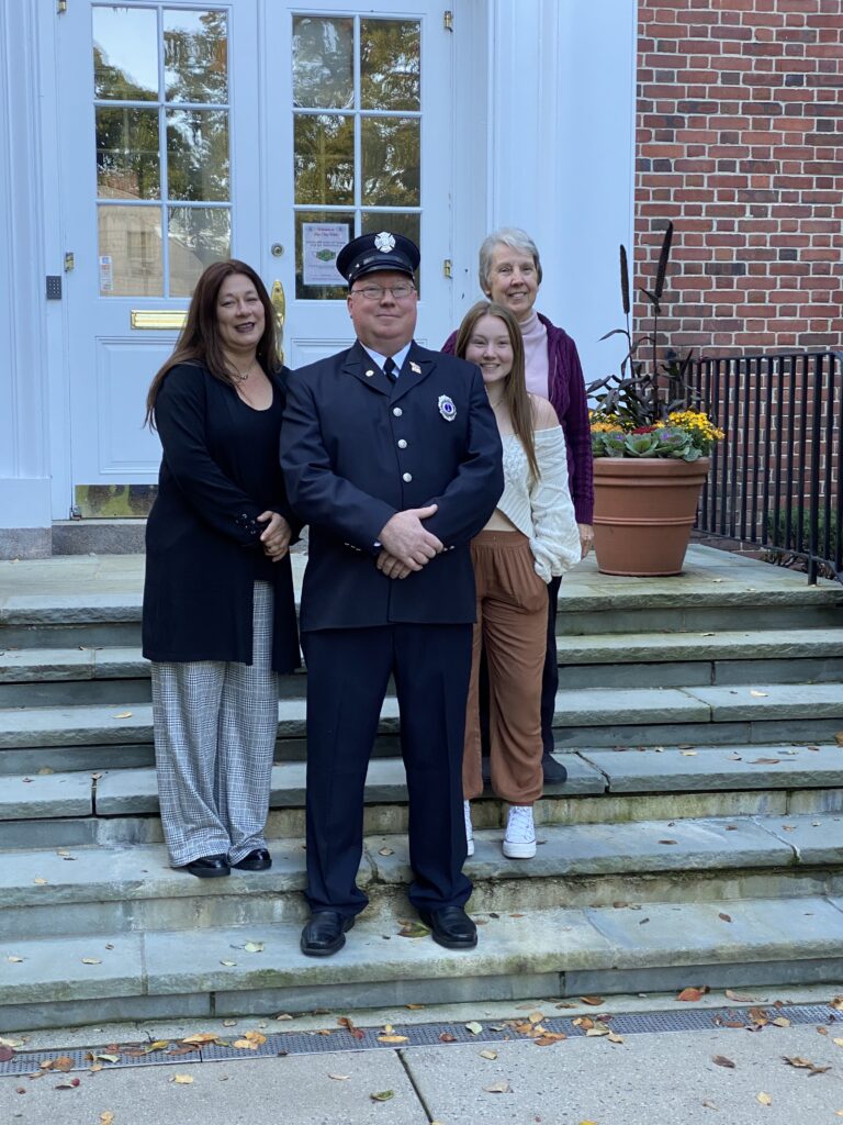 (PHOTO: Rye FD Lieutenant John Thompson with his wife Jessica (left), daughter Eliana (middle) and mother Martha (right) at his swearing in at Rye City Hall on October 18, 2022.)