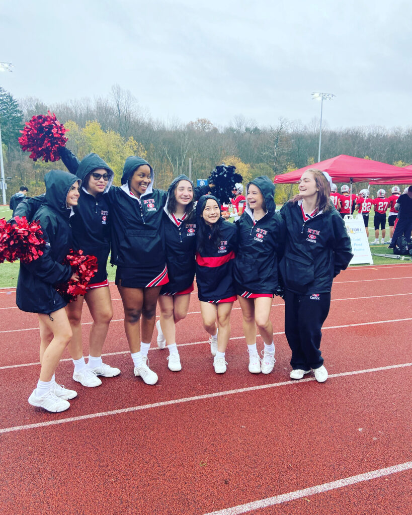 (PHOTO: Rye Girls Varsity Cheerleaders smile rain or shine.)