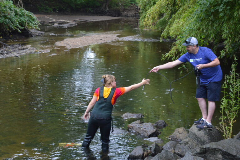 (PHOTO: Delia Bajuk, student at Rye High School and Sam Marquand, clean water advocate at Save the Sound working to deploy data loggers in the Blind Brook near the Rye High School campus.)