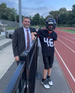 (PHOTO: Rye City School District Superintendent Eric Byrne with #46 TJ Neeves at Nugent Stadium.)