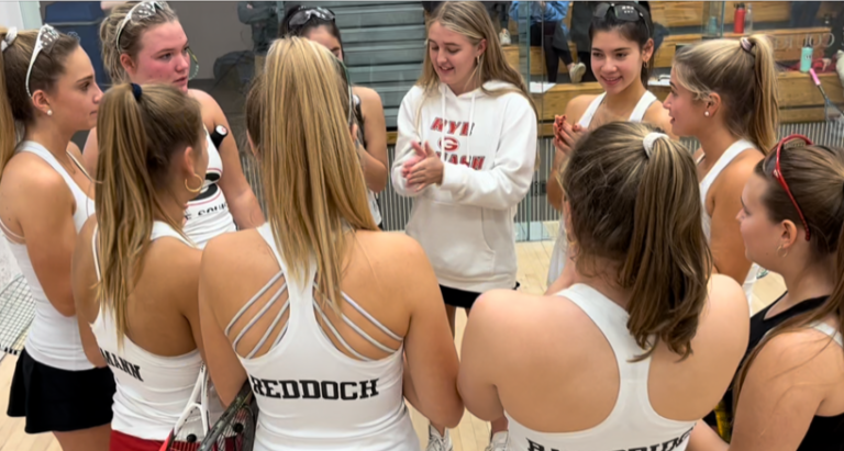 (PHOTO: Rye Girls Varsity Squash Rye 1 team huddles for their pre-game cheer at an early season tournament at Blair Academy.)