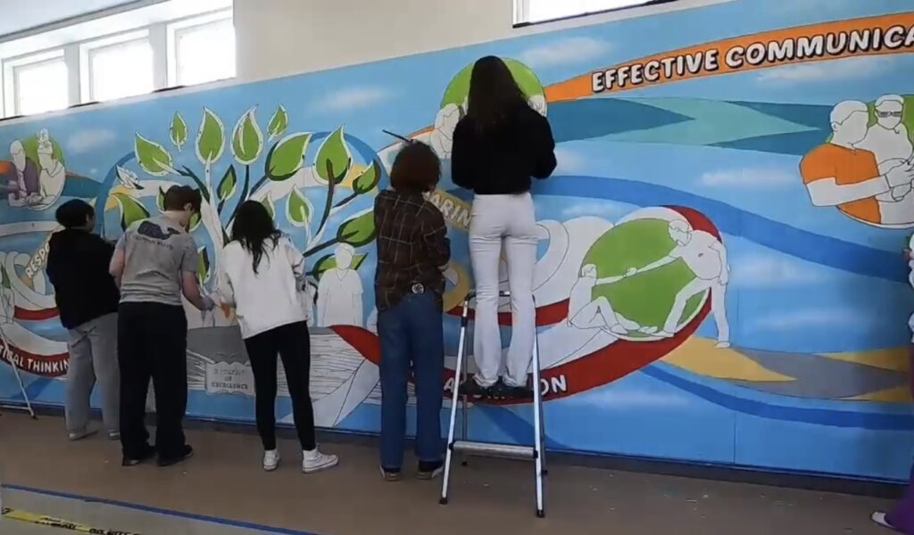 (PHOTO: Artist Joe Pimentel worked with the Rye High School Garnets class to create a mural at the High School. The mural represents the Rye Commitment and what it means to students.)
