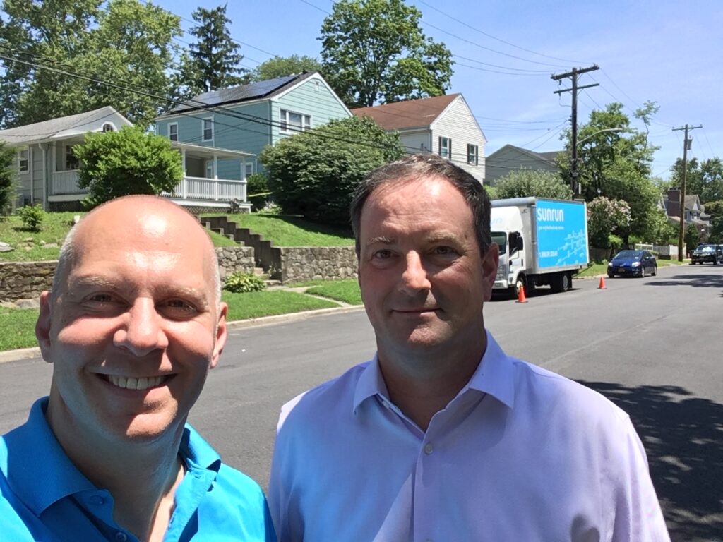 (PHOTO: Sunrun's Peter Chaitkin with Rye resident Brian Jackson in front of Jackson's home with his Sunrun solar system on the day of installation in 2019.)