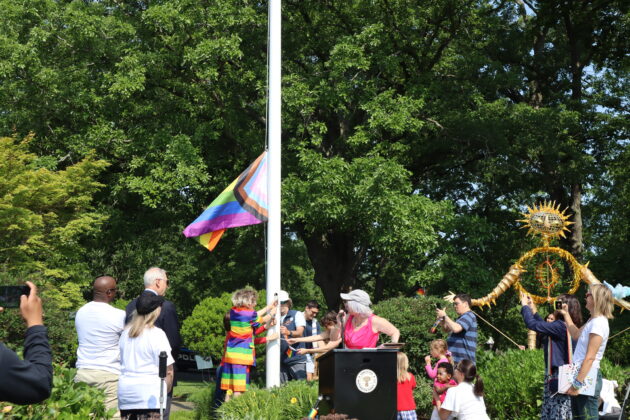 (PHOTO: Influencer Desmond Napoles and young community members raise the Pride flag at 9:30 am in Rye Town Park on Saturday, June 10, 2023. Credit: Sierra Desai.)
