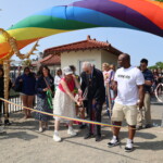 (PHOTO: Town to Rye Councilmember Pam Jaffee and Town of Rye Supervisor Gary Zuckerman cut the rainbow ribbon to commence the Pride parade in Rye Town Park on Saturday, June 10, 2023. Credit: Sierra Desai.)