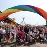 (PHOTO: The Pride parade marchers gather for a photo under the rainbow arch on the Playland boardwalk on Saturday, June 10, 2023. Credit: Sierra Desai.)