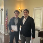 (PHOTO: Cian Keegan receives a student-athlete of the month certificate from Varsity Wrestling Coach Brian Scher.)