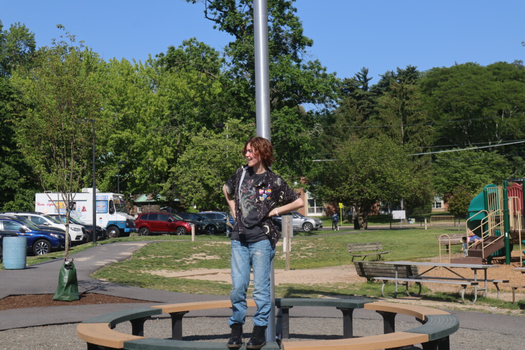 (PHOTO: Senior leader Odessa Meulbroek standing under the Pride flag at the Rye Rec to give a speech to the group at 4:30 pm. Credit: Sierra Desai.)