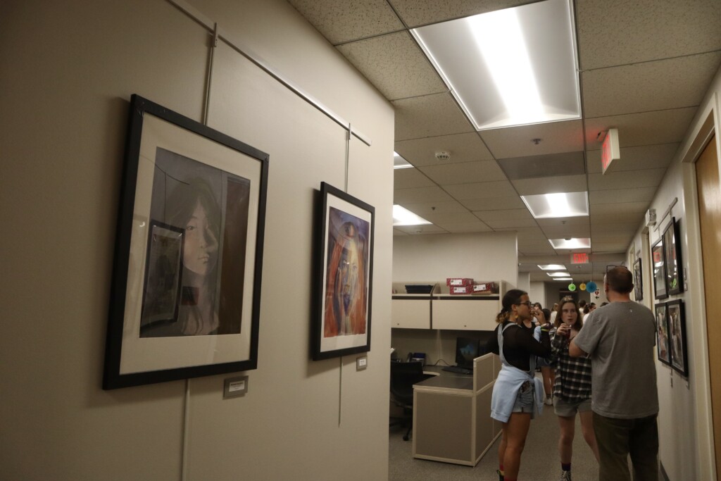 (PHOTO: Visitors view the art hung on the walls of the Rye City School District's Central Administration Building. Credit: Sierra Desai.)