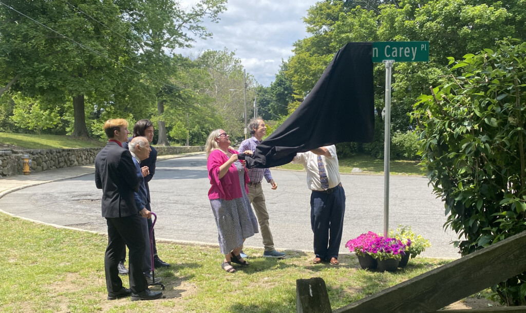 (PHOTO: The children of former Rye Mayor John Carey - Jennifer Carey Reichle, Chip Carey and Doug Carey (behind the black veil) debut John Carey Place on Friday, June 9, 2023.)