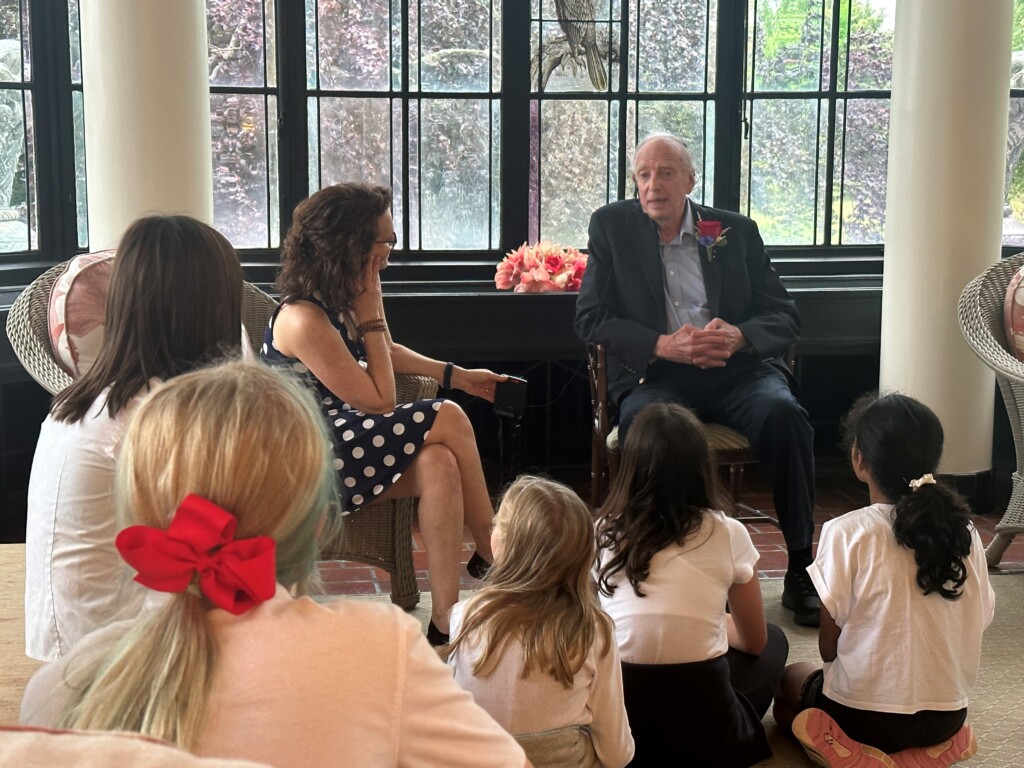 (PHOTO: Osborn Resident Robert November sitting with Osborn schoolchildren)