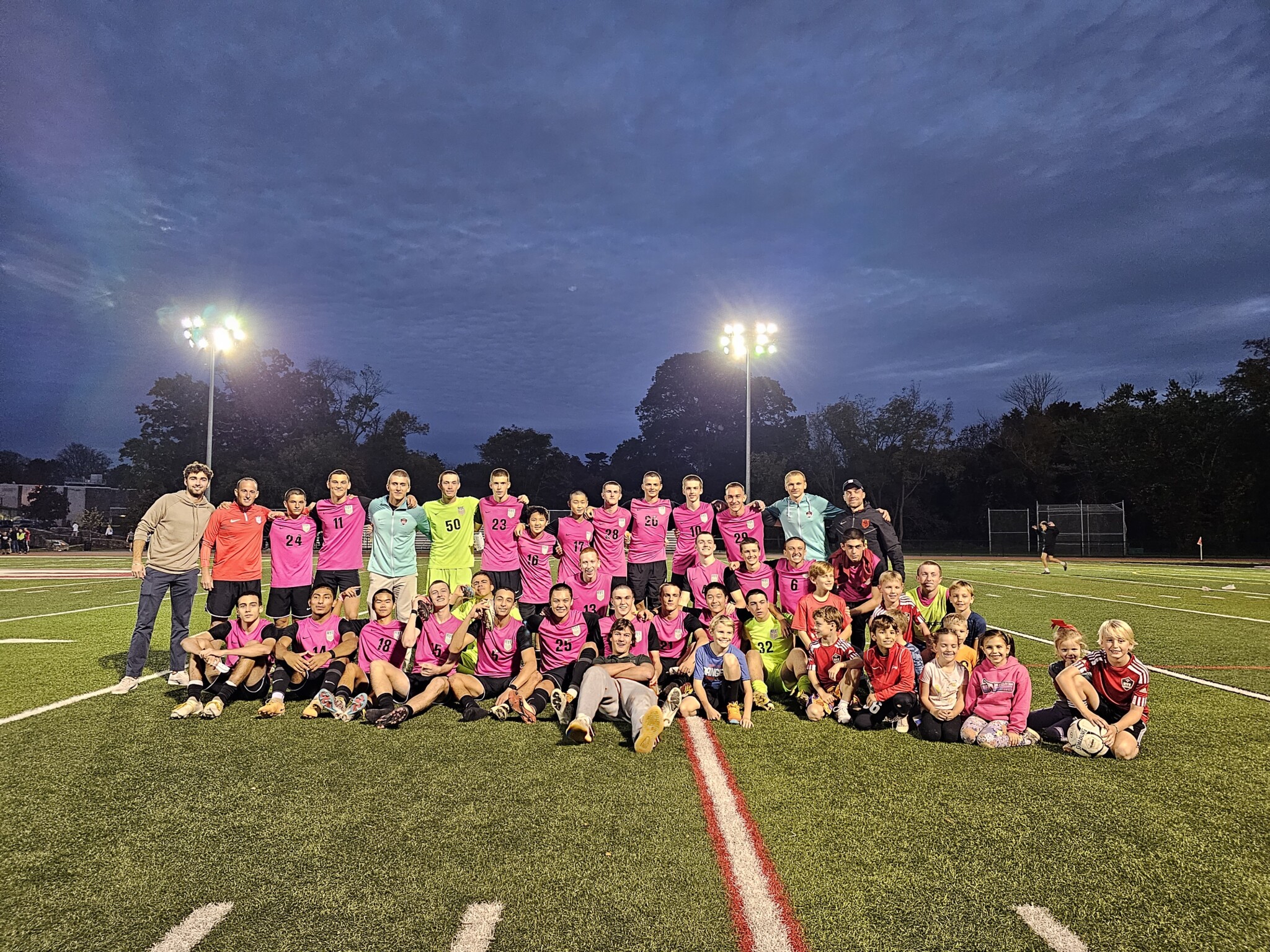 (PHOTO: The 2023 Rye Boys Varsity Soccer team, alums, and ball boys pose for a picture post-match.)