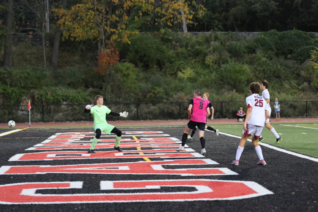 (PHOTO: Rye Boys Varsity Soccer player Tommy Broderick scores after a beautiful assist from Peter Wilmot (pictured in background).)