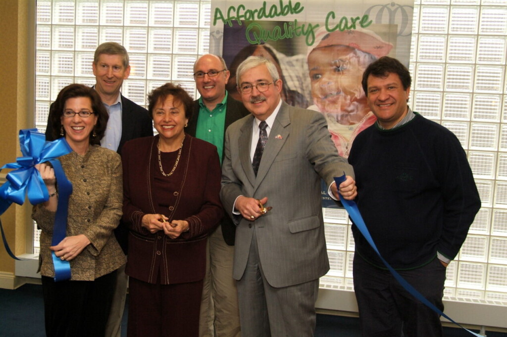 (PHOTO: 2006 Port Chester Open Door grand opening ribbon cutting with then Congresswoman Nita Lowey (in maroon) and then New York State Assemblyman George Latimer (far right).)