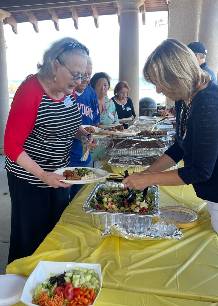 (PHOTO: SPRYE Board President Dolores Eyler serves a member at the Annual SPRYE member picnic at Rye Town Park.)
