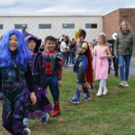 (PHOTO: Osborn Elementary School students assembling for their parade onto The Osborn retirement community campus on October 31, 2023 to celebrate Halloween.)