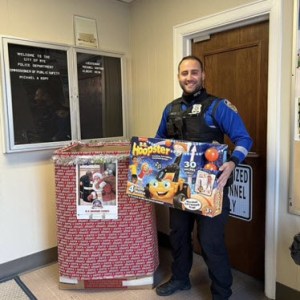(PHOTO: Rye Police Officer Joao Anjo with one of the toys donated to the Toys for Tots drive located at Rye PD headquarters.)