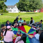 (PHOTO: Teacher Sunilda Esetivez enjoying the sunshine with 5 Steps to Five program families at Lyon Park summer of 2023.)