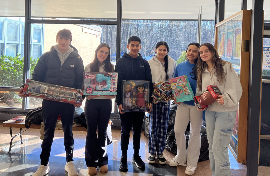 (PHOTO: Rye Neck School senior Clara Reis, winner of the 2023 Rye Youth Human Rights Award, with officers of Key Club at Rye Neck High School, with all the toys the group collected before the holidays for Toys for Tots. Left to right: Harrison Delaney, Reis, Eric Valdez, Ashley Hernandez, Rachelle Candamil, and Nicolette Capparelli.)