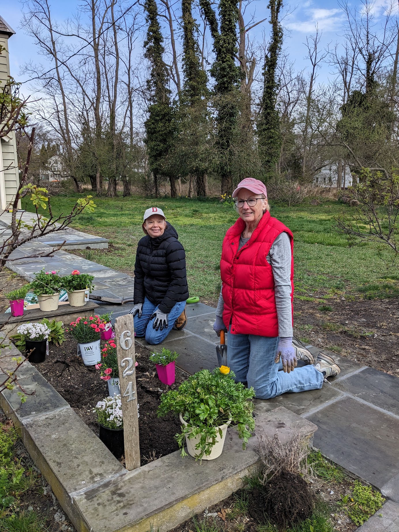 (PHOTO: Bonnie Council and Michelle New planting a pollinator garden in front of the Meeting House on April 13, 2024.)