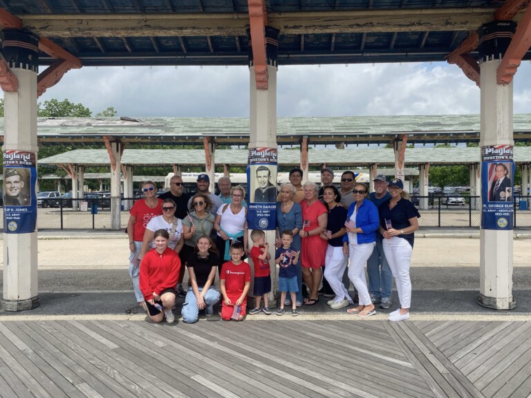 (PHOTO: The extended Dahlgren family around the banner showcasing US Navy veteran Kenneth Eugene Dahlgren. The banners are part of Playland's new Hometown Heroes program. Credit: Playland.)