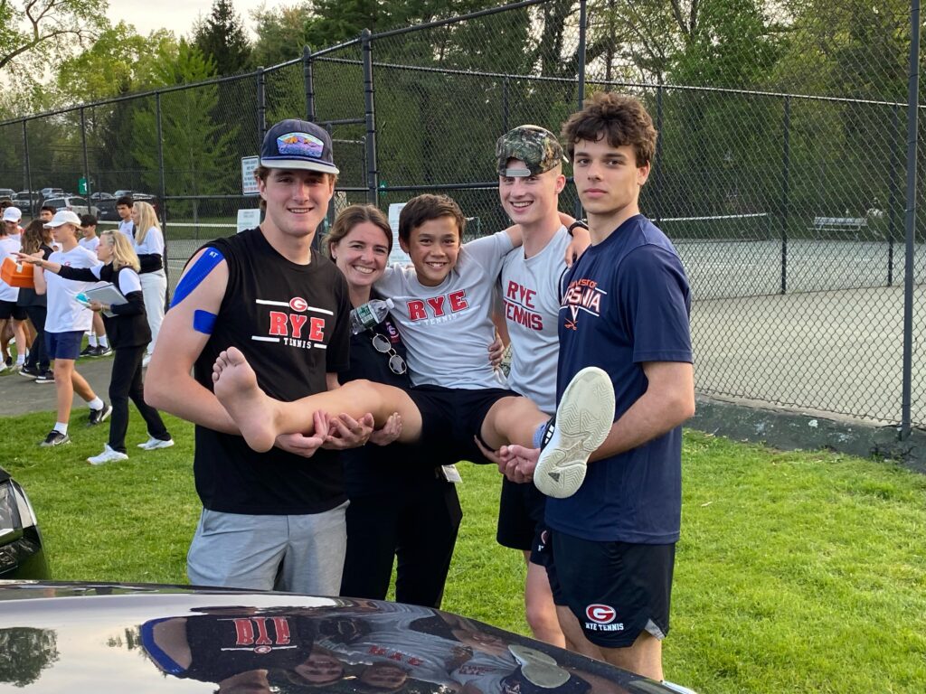 (PHOTO: Rye Boys Varsity Tennis team trainer Erin Madden (second from left) with the team's three captains: seniors Henry Bagley, Henry Paul and Nicolas Echlov. (middle: unidentified)).