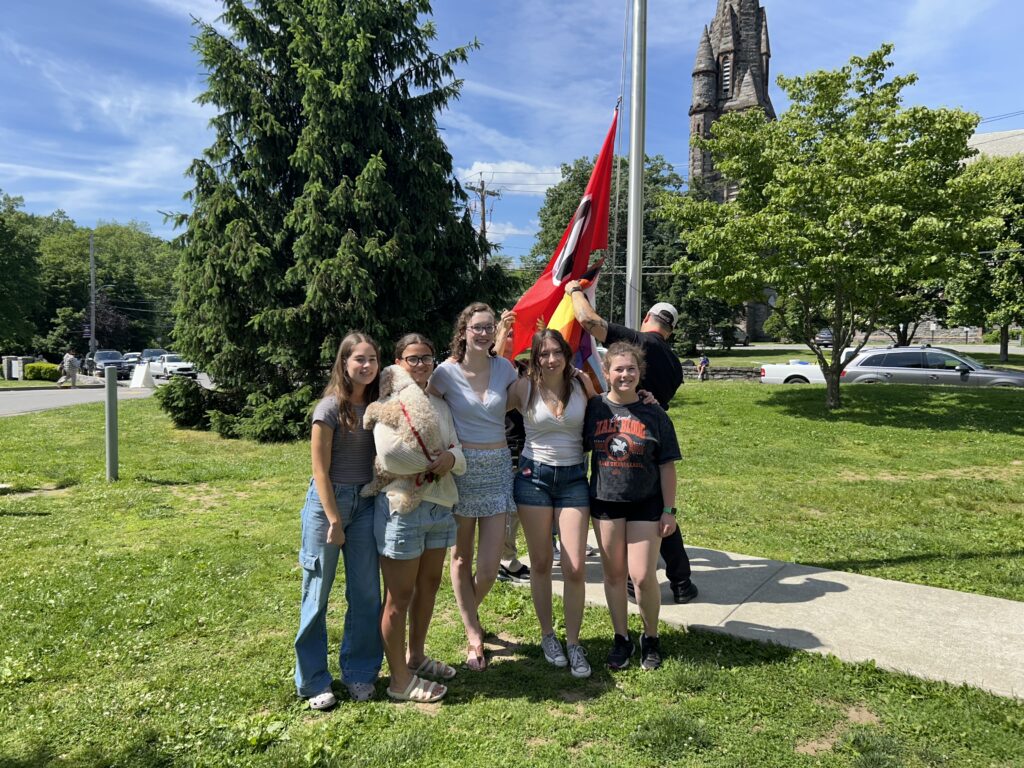 (PHOTO: Rye High School GSA members at the 4th annual Pride flag raising on Friday, May 31, 2024 (left to right): Emily Schmidt, Izzy Godden (holding Gizmo), Shannon Haines, Delia Degnan and Rebekah Golub.)