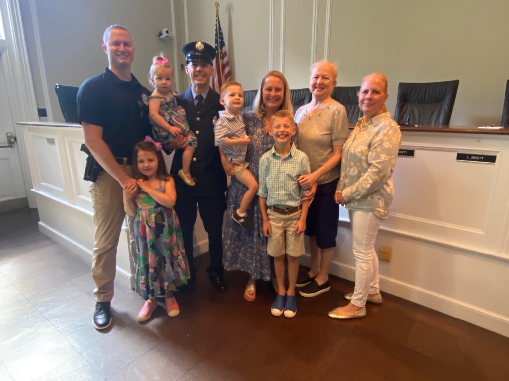 (PHOTO: New Rye FD Lieutenant Joseph Ganci with his family at his swearing on at Rye City Hall on June 10, 2024 (left to right) brother James Ganci, Madeline (age 5), Molly (age 1 - held by Ganci), Peter (age 3), wife Allison, Jack (age 8), mother Peggy Ganci, mother-in-law Cheryl Daly.)