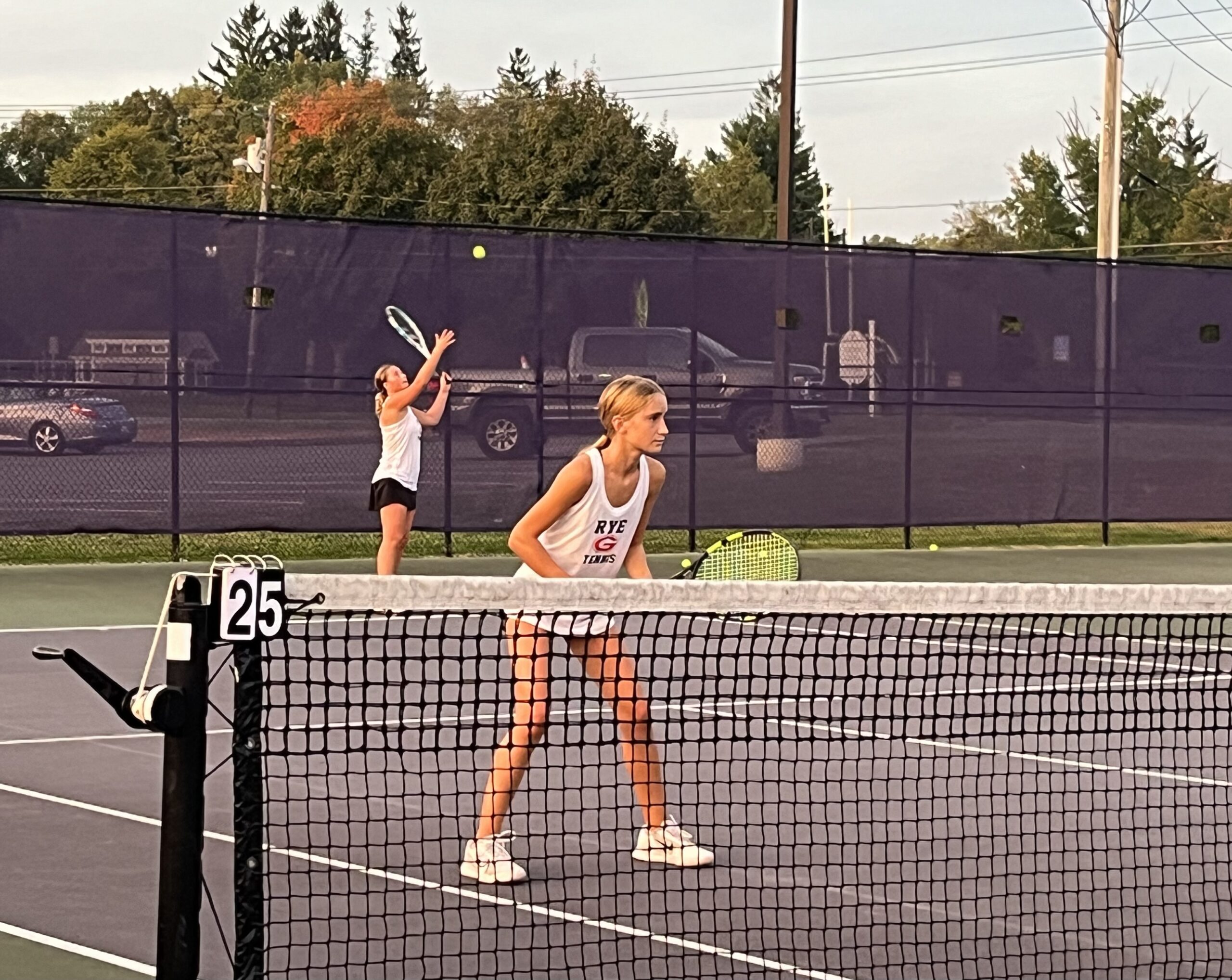 (PHOTO: Girls Tennis player Caroline May serves as her partner Eliza Relyea prepares for the volley during the duo's second set.)