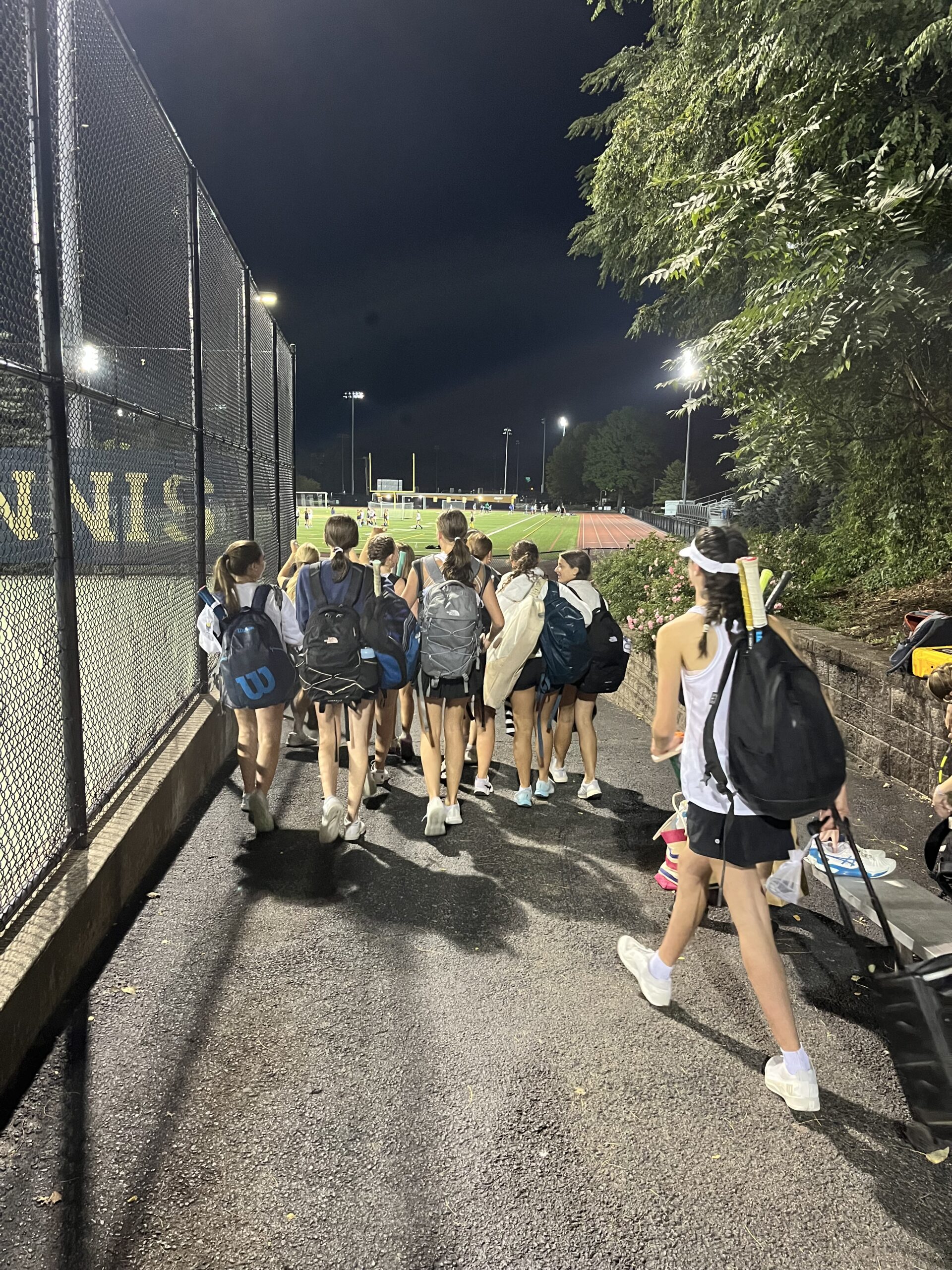 (PHOTO: The Girls Varsity Tennis Team races to the bus after a busy week of matches, winning four straight.)