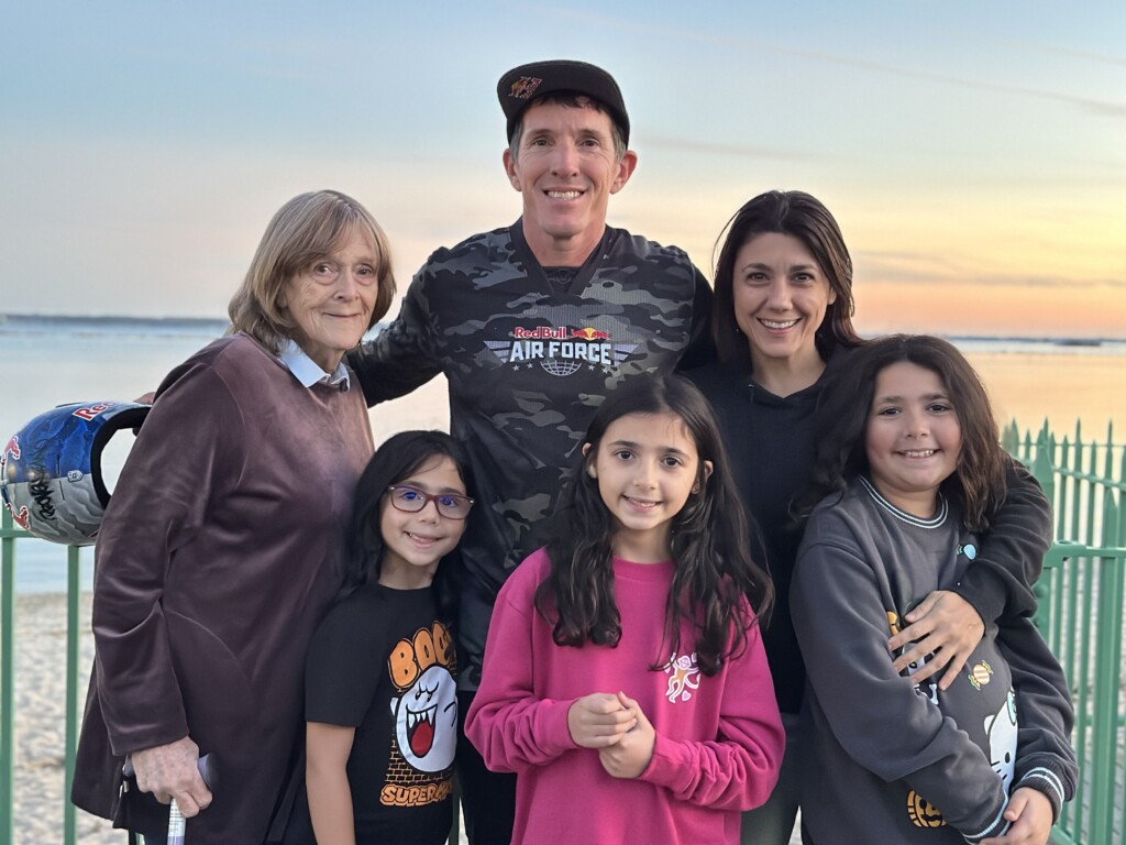 (PHOTO: Jeff Provenzano – 1994 Rye High School grad, professional stuntman and member of the Red Bull Air Force – skydived onto Rye Playland Beach on Saturday, October 12th at 6:00pm. Provenzano (center) with Brigitte Loritz (left, his mother), Stephanie Paciullo (right, his girlfriend) and the kids Emmy Stone (left) Izzy Stone (middle) and Addie Stone (right).)