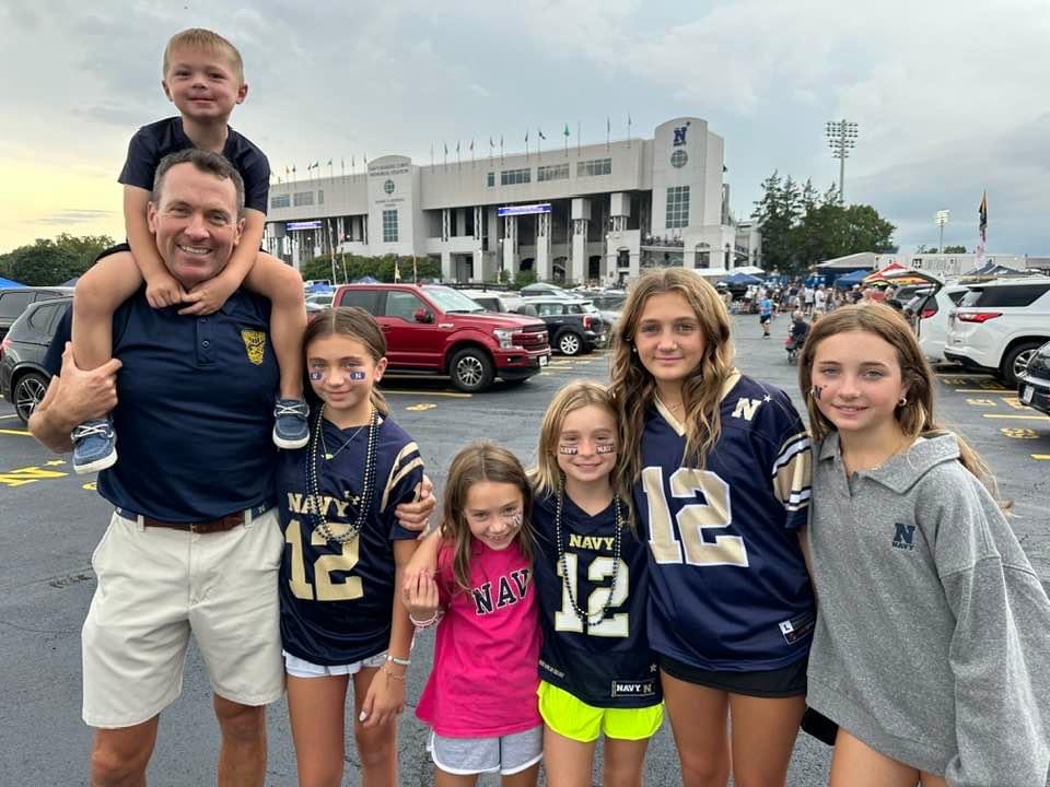 (PHOTO: US Marine Corps veteran and Bradford Avenue resident Tony Bancroft in 2023 at a Navy football game with his children.)